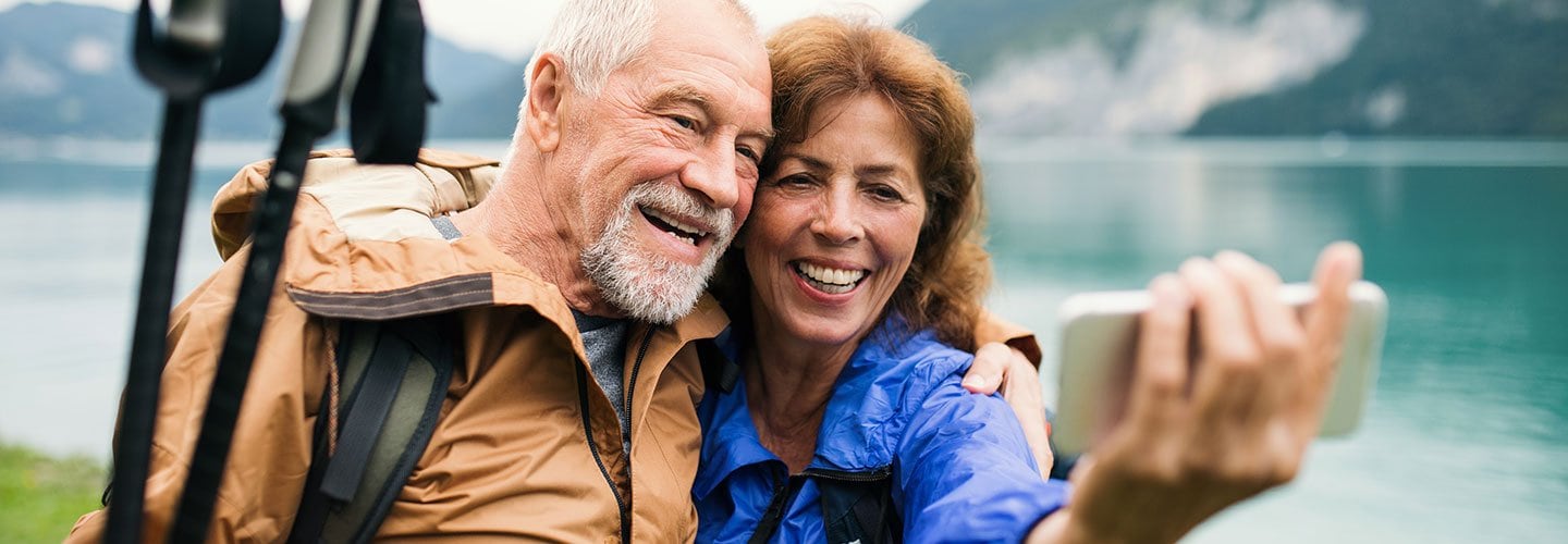 man and woman taking selfie in front of lake