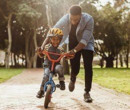 father holding son riding bike