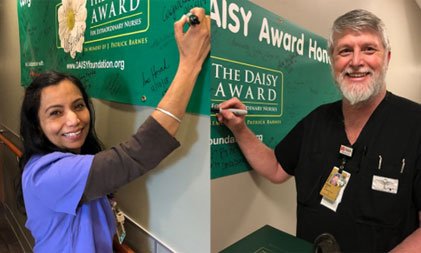 two daisy award nurses signing banners