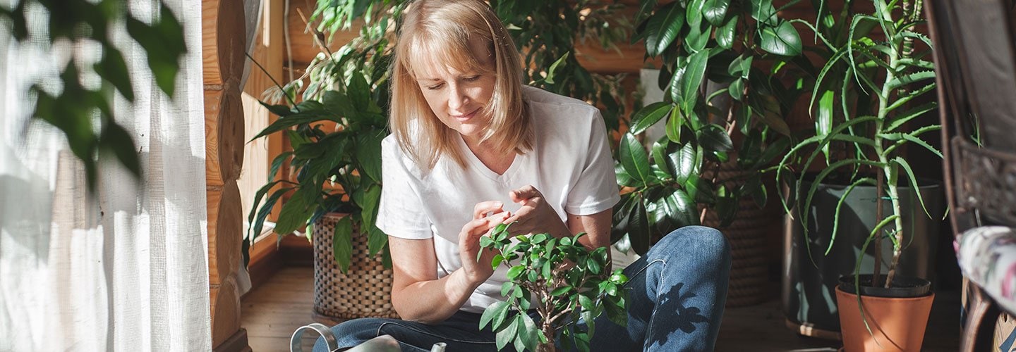 woman sits on ground with potted plant