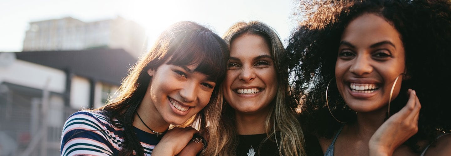 three women similing together outside