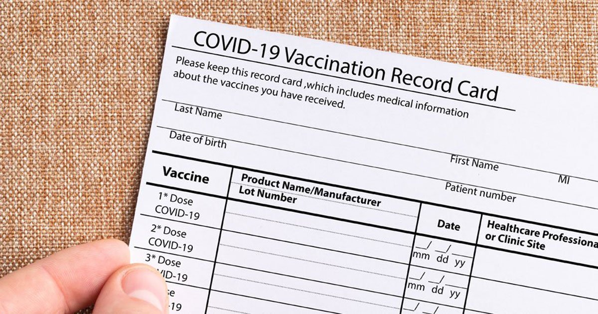 fingers holding a covid-19 vaccine card