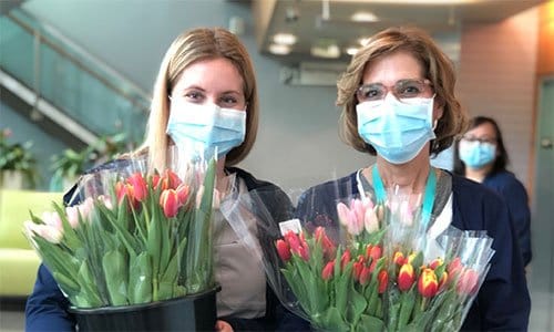 two nurses holding buckets of tulips